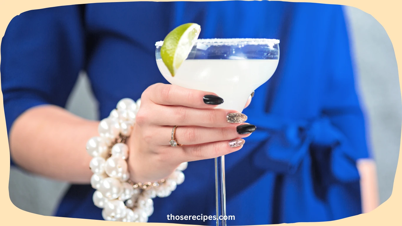 A sparkling drink with lime and mint garnishes served in a wine glass.