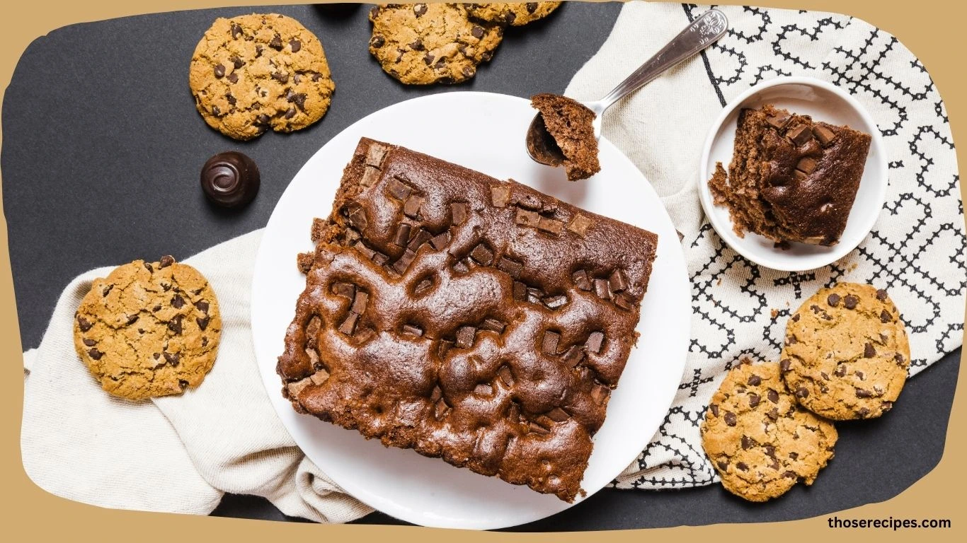 A whole chocolate pound cake on a white serving platter, garnished with chocolate shavings.