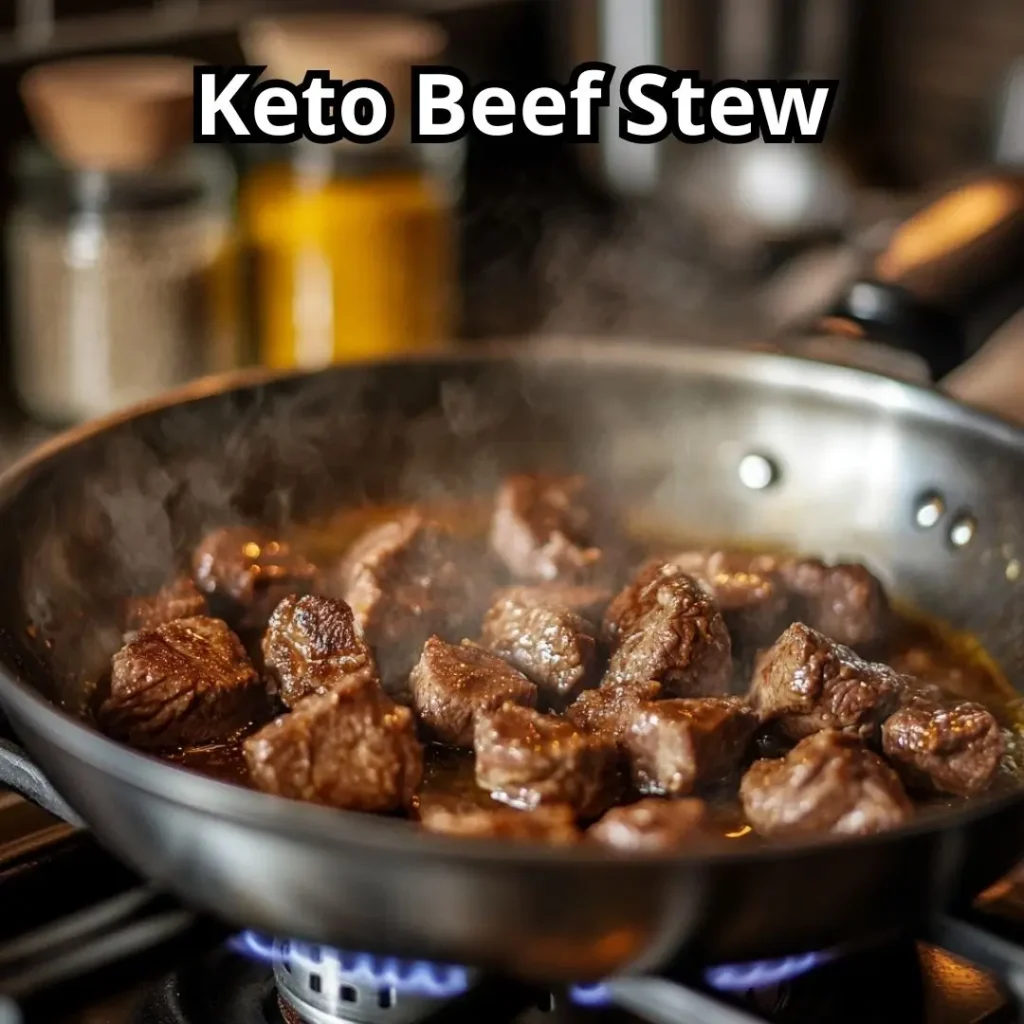 Beef chunks browning in a skillet, cooking in olive oil with a golden crust forming.